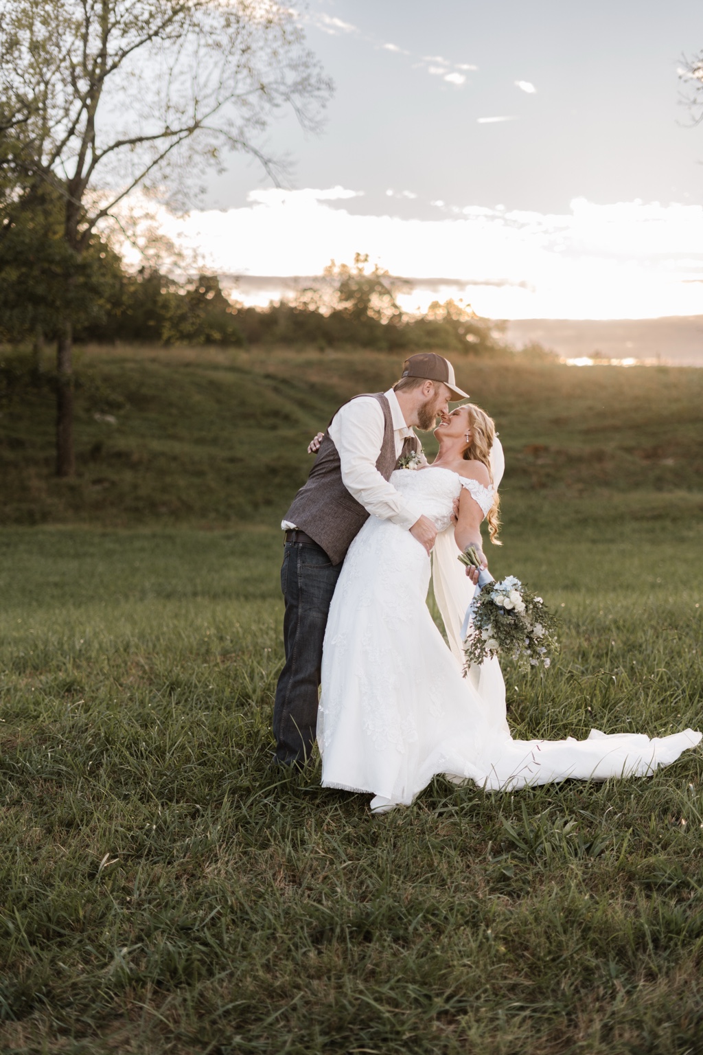 Newlyweds sharing a kiss in a sunlit field